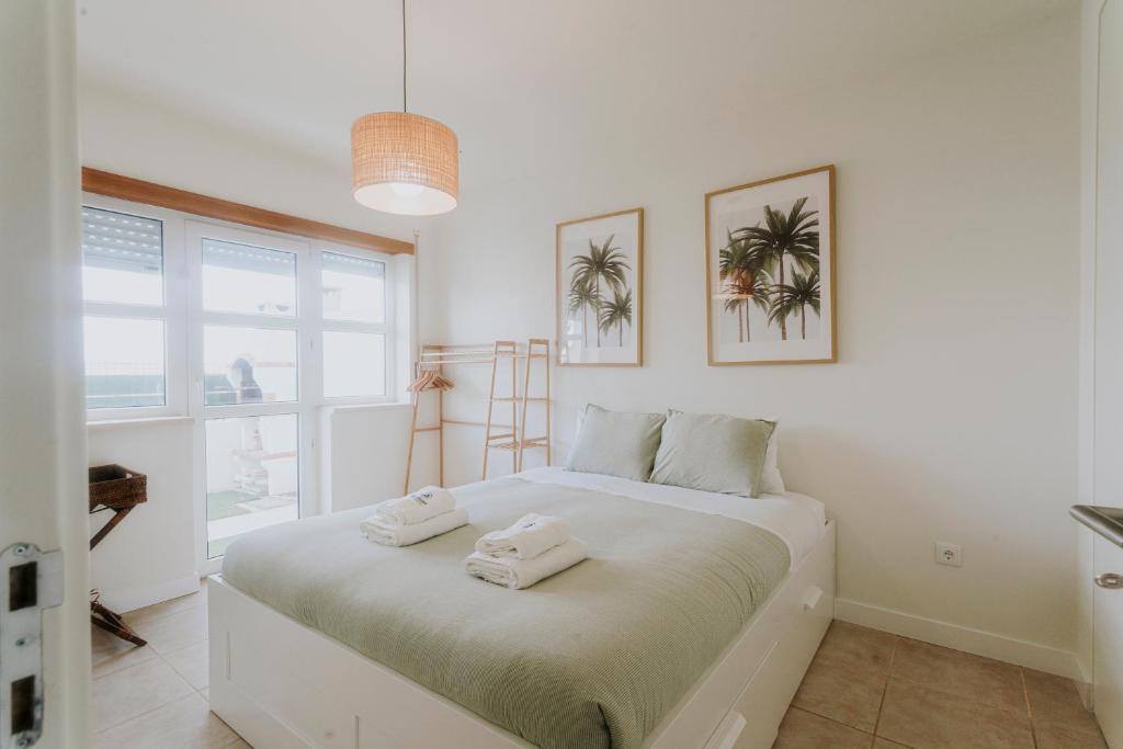 a white bedroom with a bed with towels on it at Best Houses 40 - You me and the sea in Ferrel