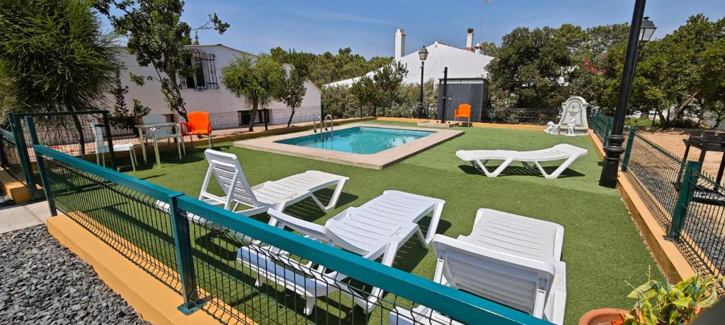 een groep witte stoelen en een zwembad bij Finca los Barrancos in Lepe