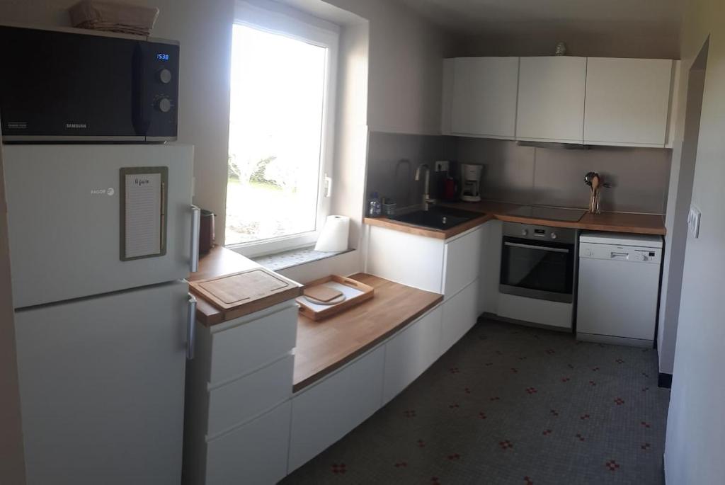 una pequeña cocina con armarios blancos y una ventana en Ty Ar Goël, en Camaret-sur-Mer