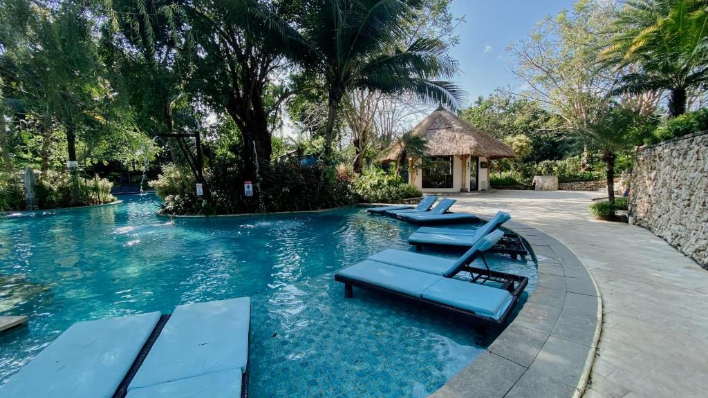 a swimming pool with lounge chairs in a resort at Esco Luxe Jimbaran in Jimbaran