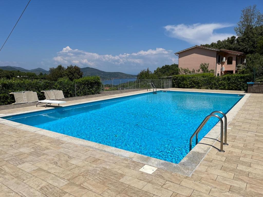 a swimming pool with blue water in a yard at Residenza Le Agavi in Capoliveri in Capoliveri