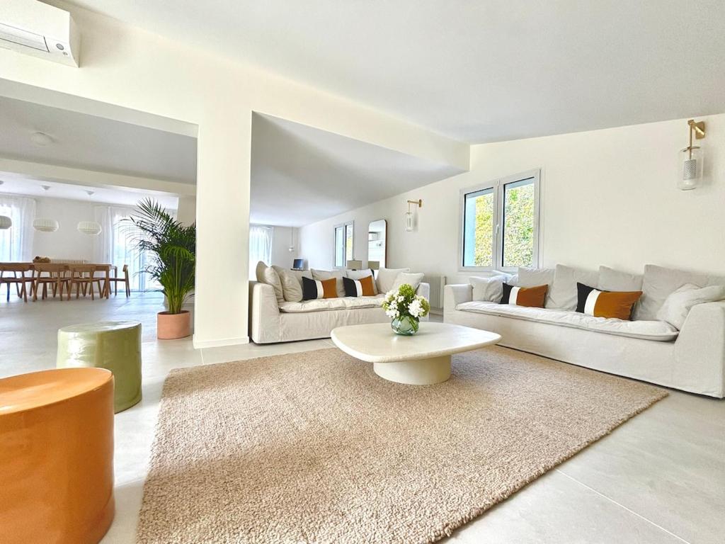 a living room with two couches and a table at Villa luxueuse avec piscine chauffée in Gujan-Mestras