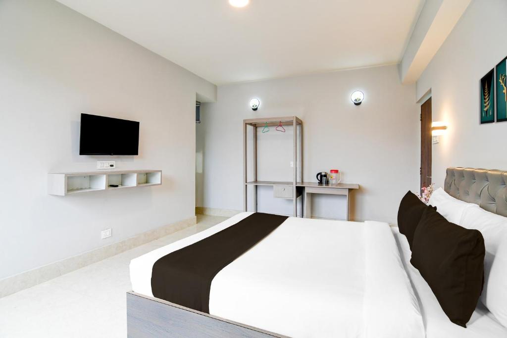een slaapkamer met een bed en een tv aan de muur bij Hotel O Vaisravana in Gangtok