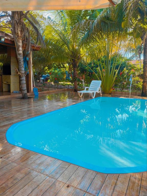 a blue swimming pool with a chair and palm trees at Pousada Rancho Dona Lú Comfort in Pereira Barreto