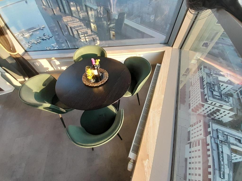 a table and chairs in a room with a window at SeaTowers 28 TOP FLOOR WATERFRONT PENTHOUSE! Sea & City PANORAMIC VIEW from GLASS CORNER TRIANGLE! 75m2! Terrace! Short&Long Stay! Parking! in Gdynia