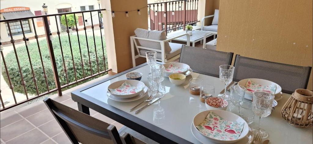 a table with dishes and glasses on a balcony at Casa Flamingolf Apartment in Fuente Alamo