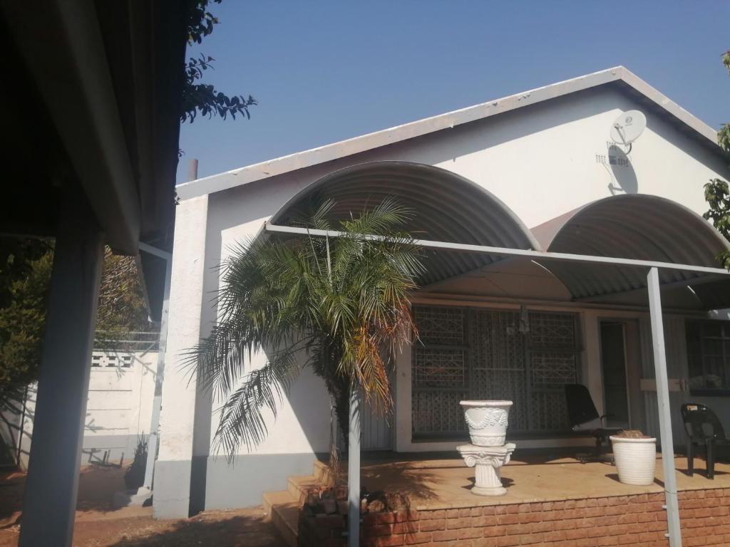 una casa blanca con una palmera delante en Foxtrot Guest House, en Pretoria