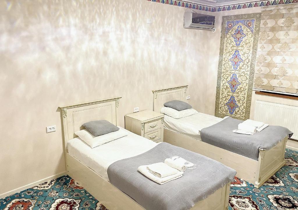 a bedroom with two beds and a window with a mosaic at Faxriddin East Hotel in Bukhara