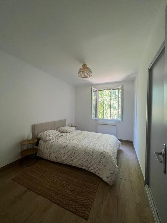 a white bedroom with a bed and a window at T3 au calme bien desservi à 10 minutes du Centre in Avignon