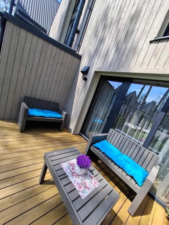 a patio with a table and a bench on a deck at Kotedžas poilsiui in Palanga