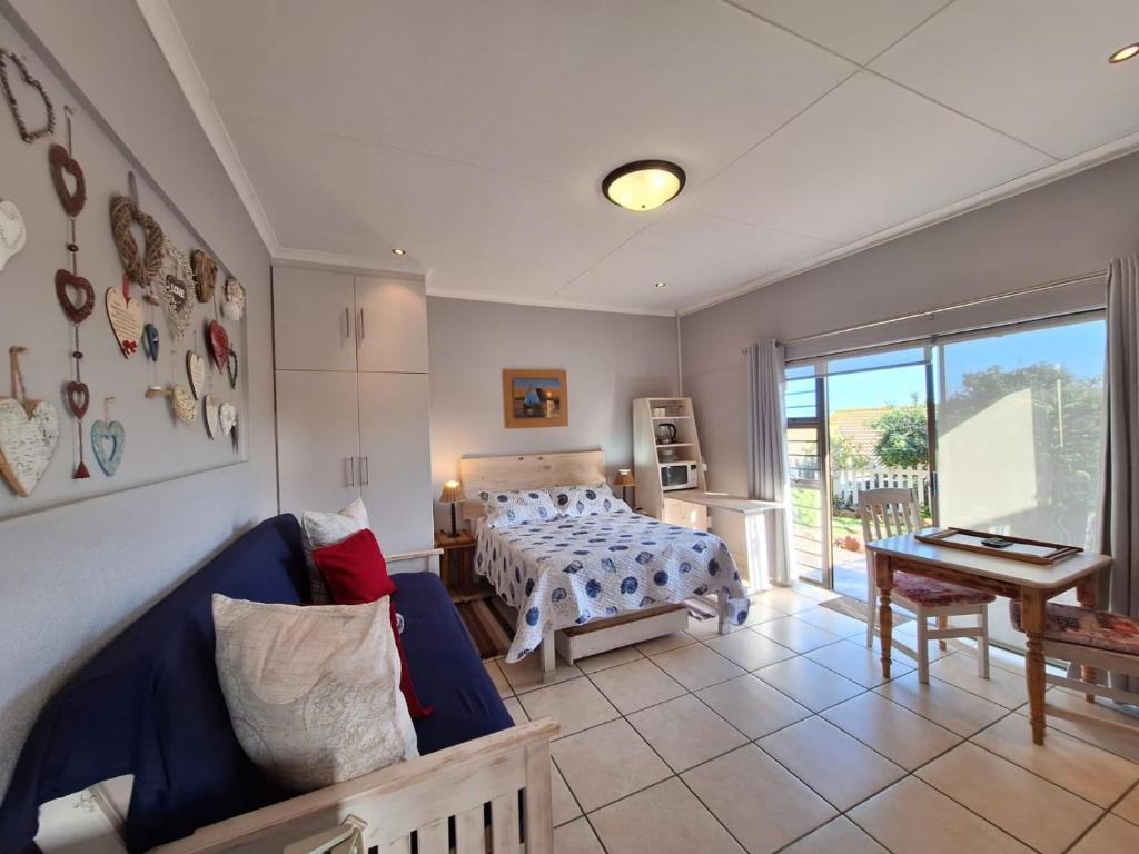 a bedroom with a bed and a couch and a table at Mooisig oornagverblyf in Mossel Bay