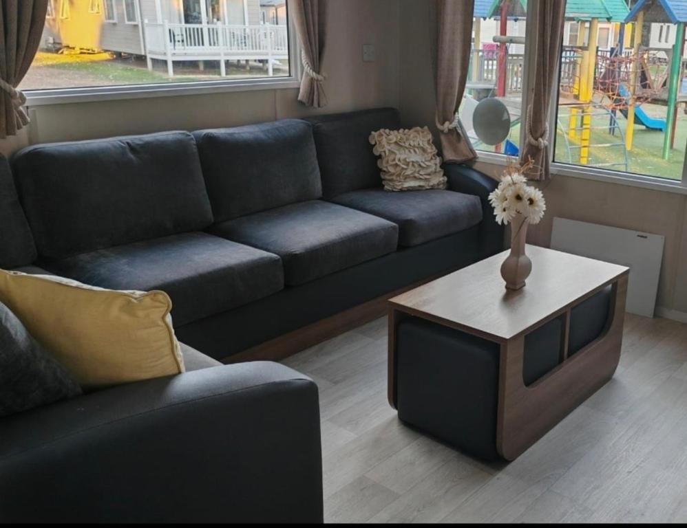 a living room with a blue couch and a table at 9 Fairway, Hopton Holiday Park - Three bedroom, sleeps 6, kitchen, lounge and dining area - Minimum 3 night breaks in Hopton on Sea