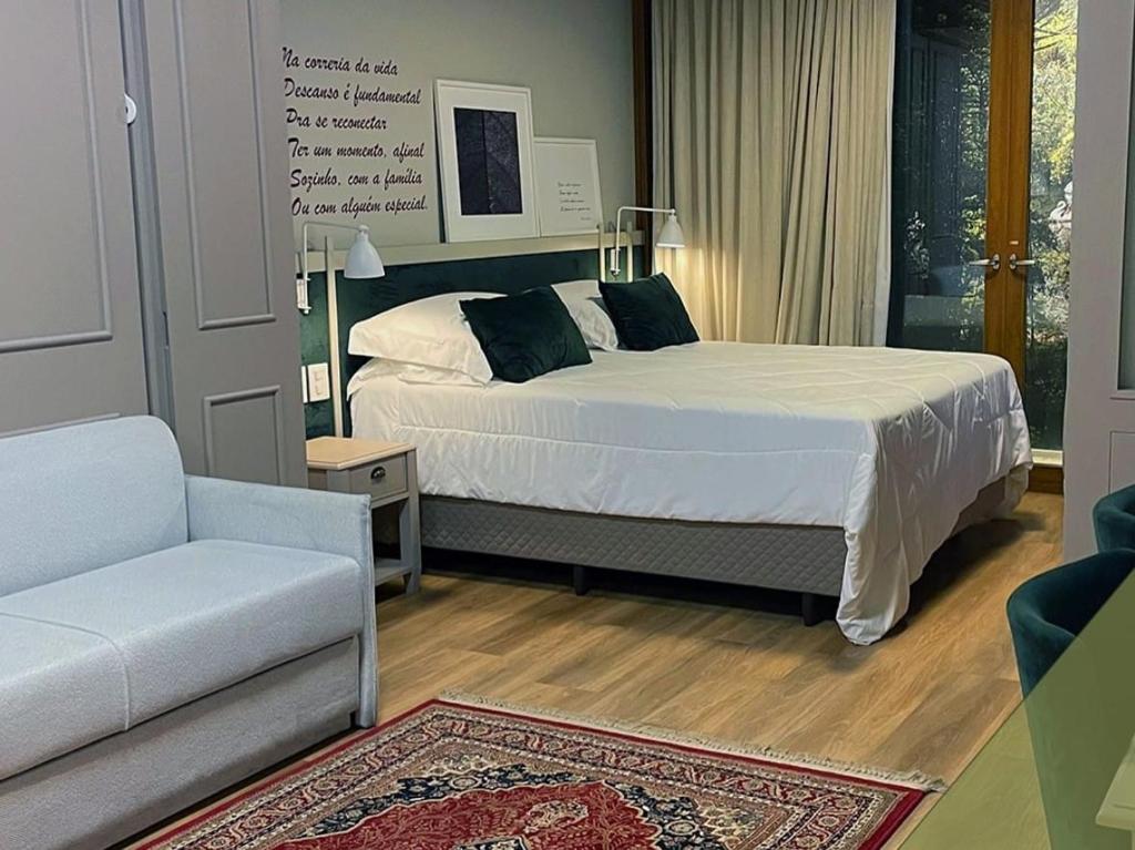 格拉玛多Locar in Gramado, Quarto em hotel, Natal-Luz, Quarto Bairro Planalto do Lago N, Aconchegante, frente para Lago N的一间卧室配有一张床、一把椅子和一张沙发
