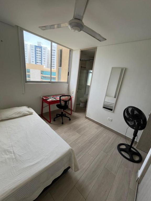 a bedroom with a bed and a table and a window at HABITACIÓN CENTRAL EN CASA FAMILIAR, A 10 minutos de la playa in Santa Marta