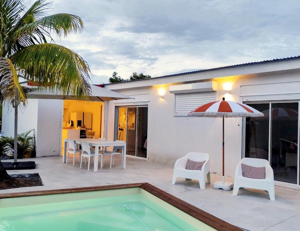 a patio with a table and chairs and an umbrella at La petite villa in Le Gosier