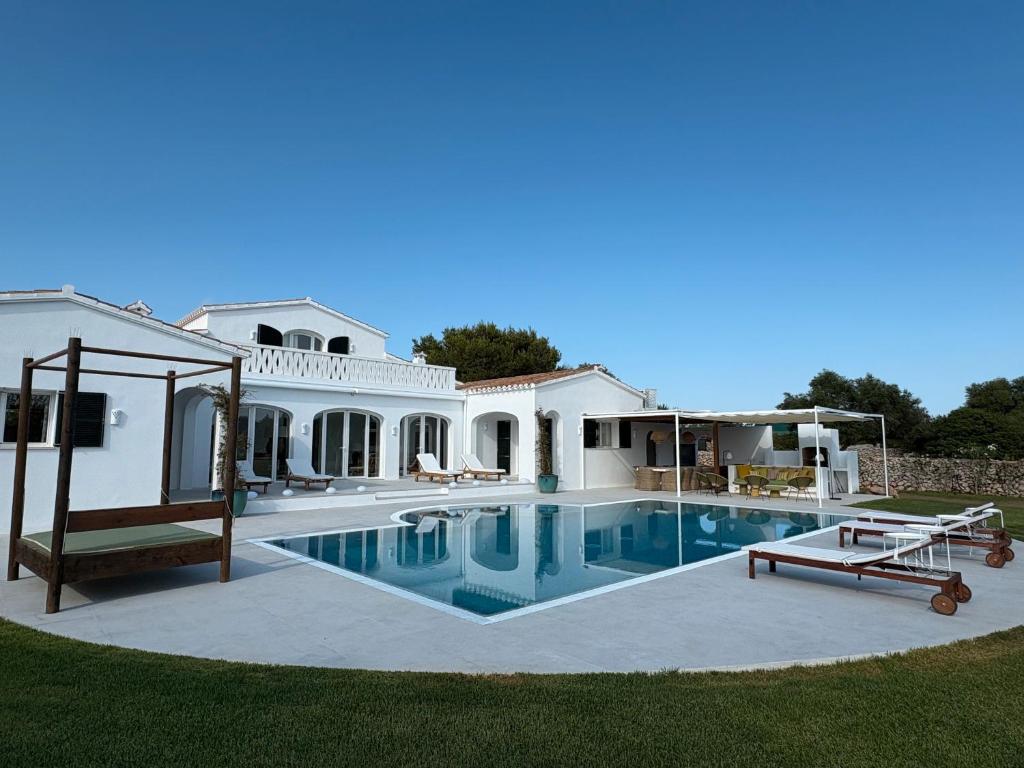 a large white house with a swimming pool at Villa Estrellita Sant Lluis in Sant Lluis