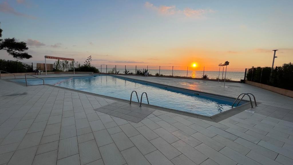 una grande piscina con un tramonto sullo sfondo di Chez Céline & Rudi a Moriani-Plage