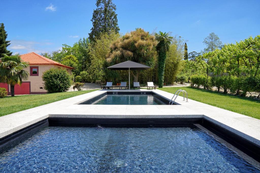 a swimming pool in a yard with an umbrella at Casa de Docim in Fafe