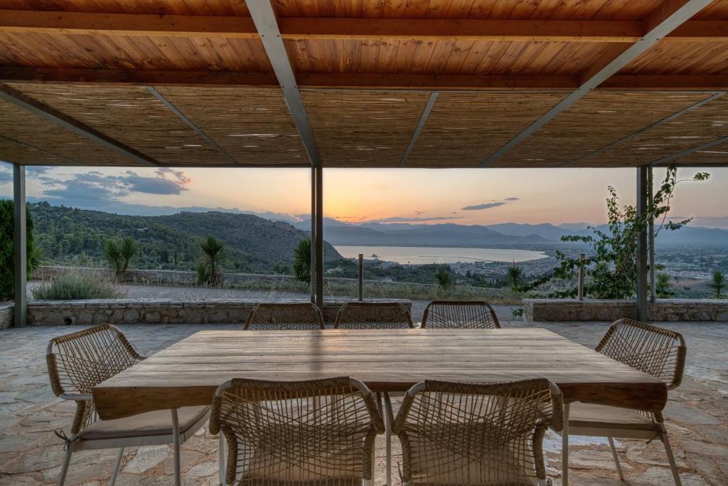 a large wooden table with chairs on a patio at Finca Nafplio Hills, spectacular sea view in Nafplio