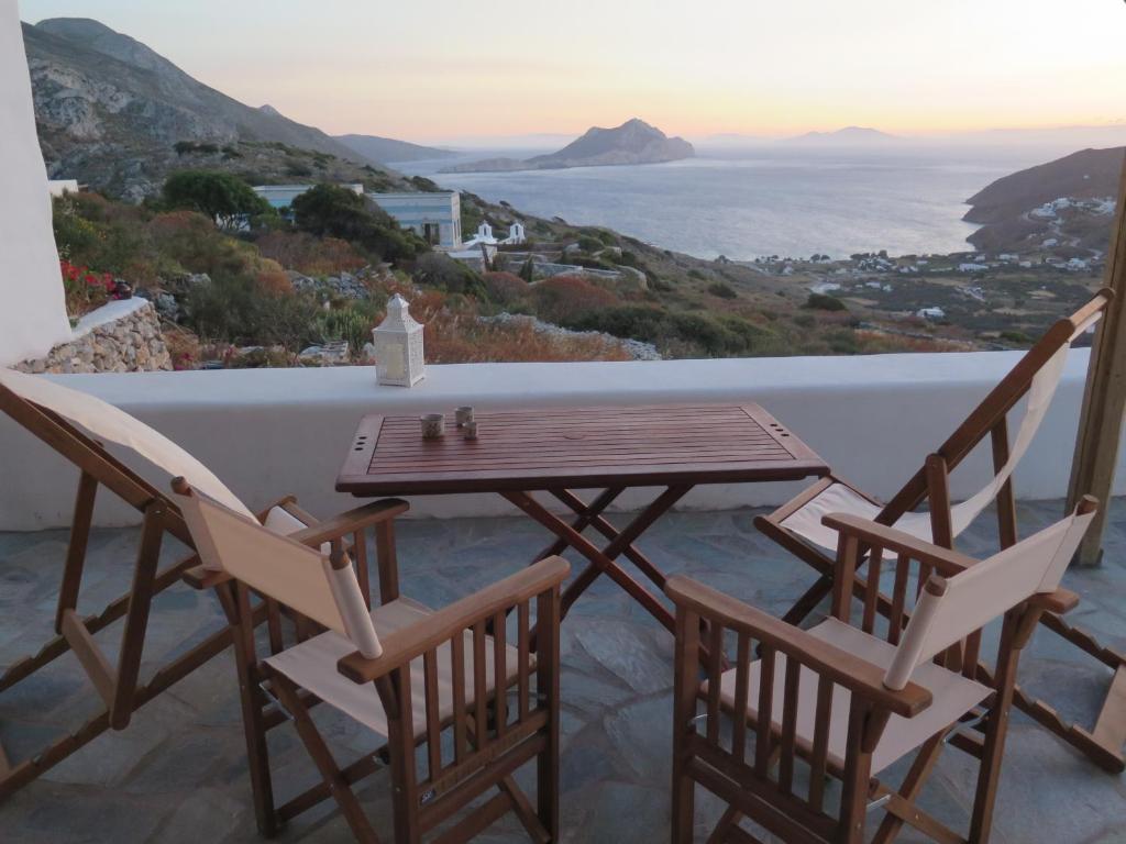 een tafel en stoelen op een balkon met uitzicht op de oceaan bij Kaminaki Amorgos in Órmos Aiyialís