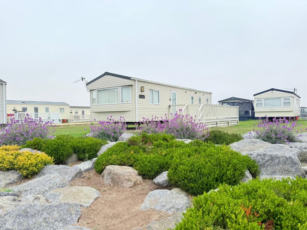 a house and a garden with rocks and flowers at Pebbles in Selsey