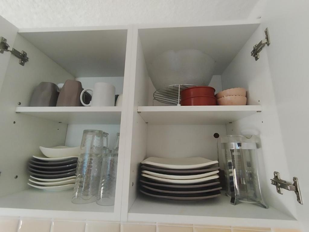 a white cabinet filled with plates and dishes at Appartement plein centre sauze in Enchastrayes