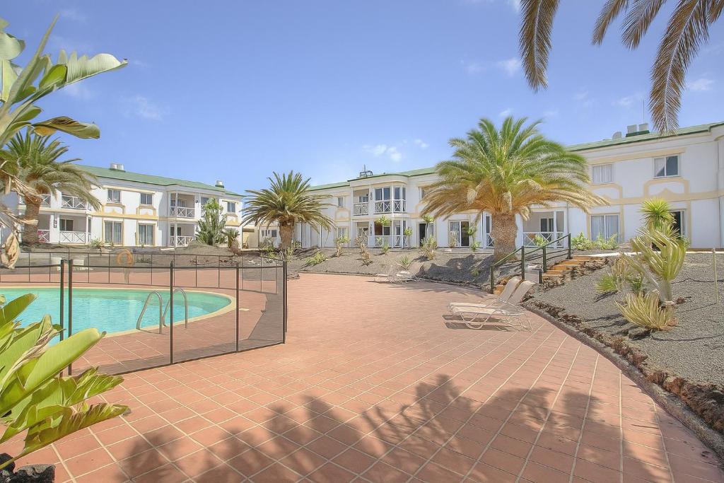 a resort with a swimming pool and palm trees at Apartamento Verdemare in Corralejo