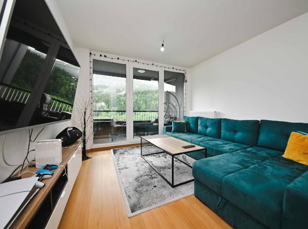 a living room with a blue couch and a table at Bjelašnica Ski View Apartment in Bjelašnica