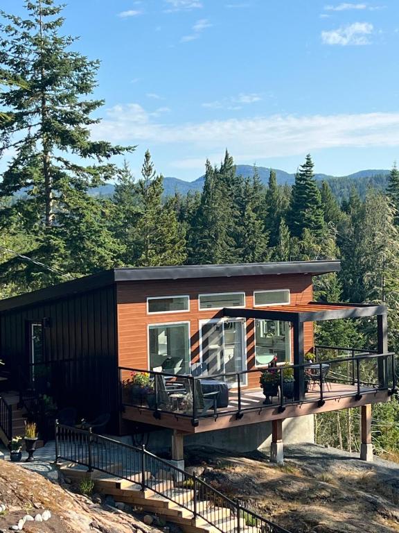 a cabin in the woods with a large deck at Serene Forest Retreat in Sooke