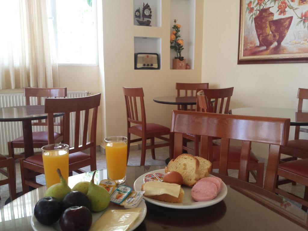 a table with a plate of food and two glasses of orange juice at Dimitra Hotel in Loutra Edipsou