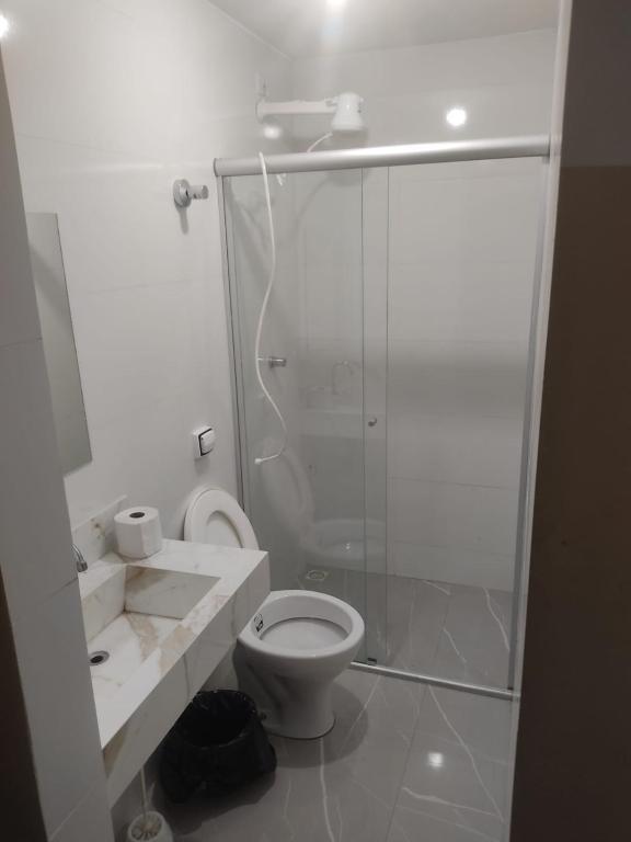 a white bathroom with a shower and a toilet at Hotel Marques in Coração de Jesus