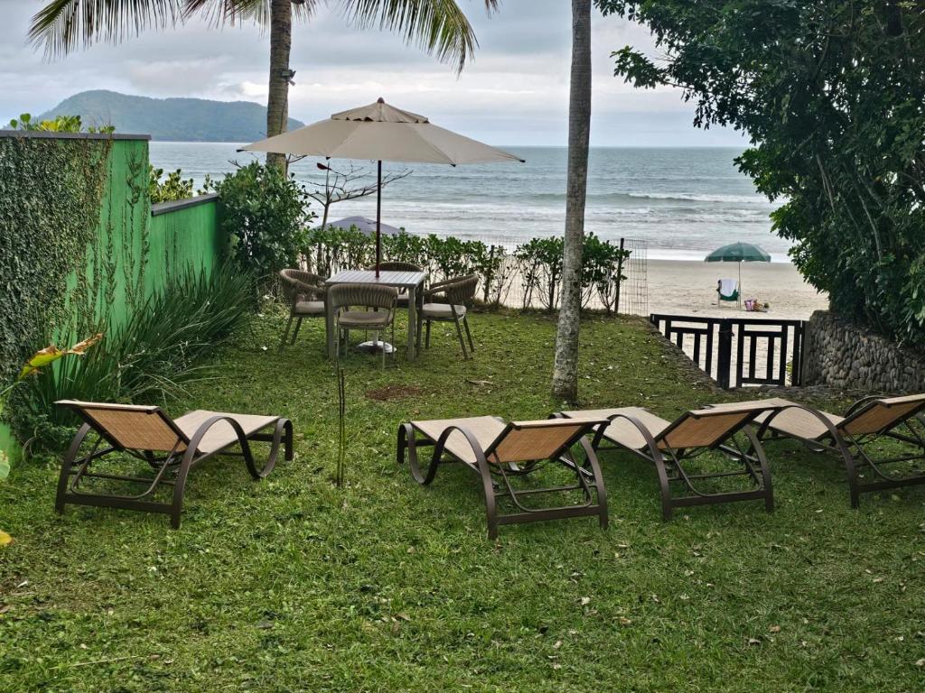 un gruppo di sedie e un tavolo con un ombrellone sulla spiaggia di Casa pé na areia na Praia de Juquehy a São Sebastião