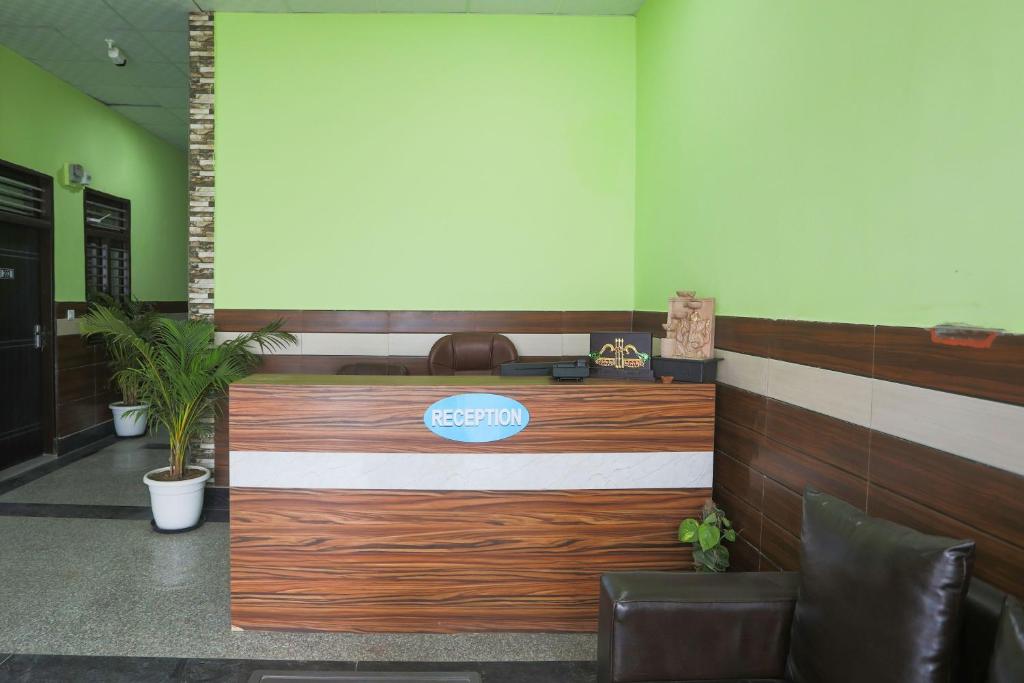 Un vestíbulo con un mostrador de recepción con un cartel. en Capital O A-one, en Manesar