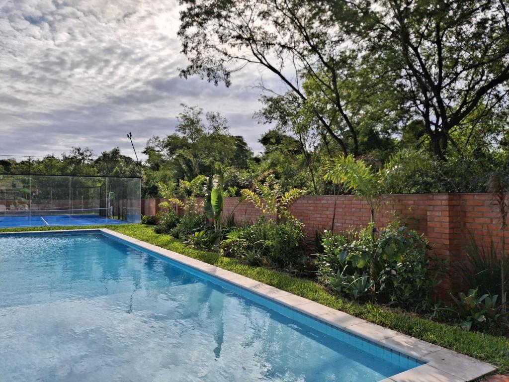 a swimming pool in a yard with a brick fence at Departamento Resort zona aeropuerto in Luque