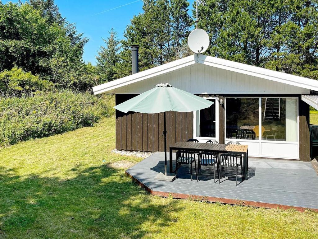 um pátio com uma mesa e um guarda-sol em 6 person holiday home in Fjerritslev em Fjerritslev
