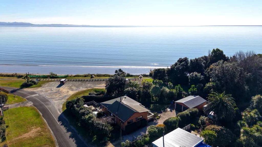 Pohara Sands - Family Beach House في Pohara: اطلالة جوية على منزل بجانب الماء