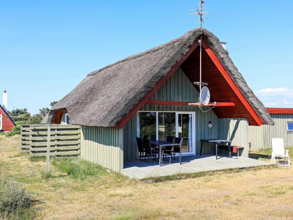 a small hut with a thatched roof with a table at 6 person holiday home in Hvide Sande-By Traum in Hvide Sande