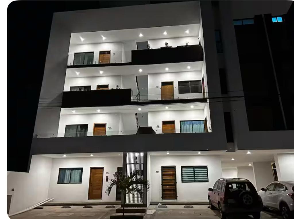 Un gran edificio blanco con coches aparcados en un estacionamiento. en Dto amplio cerca de playa, en Mazatlán