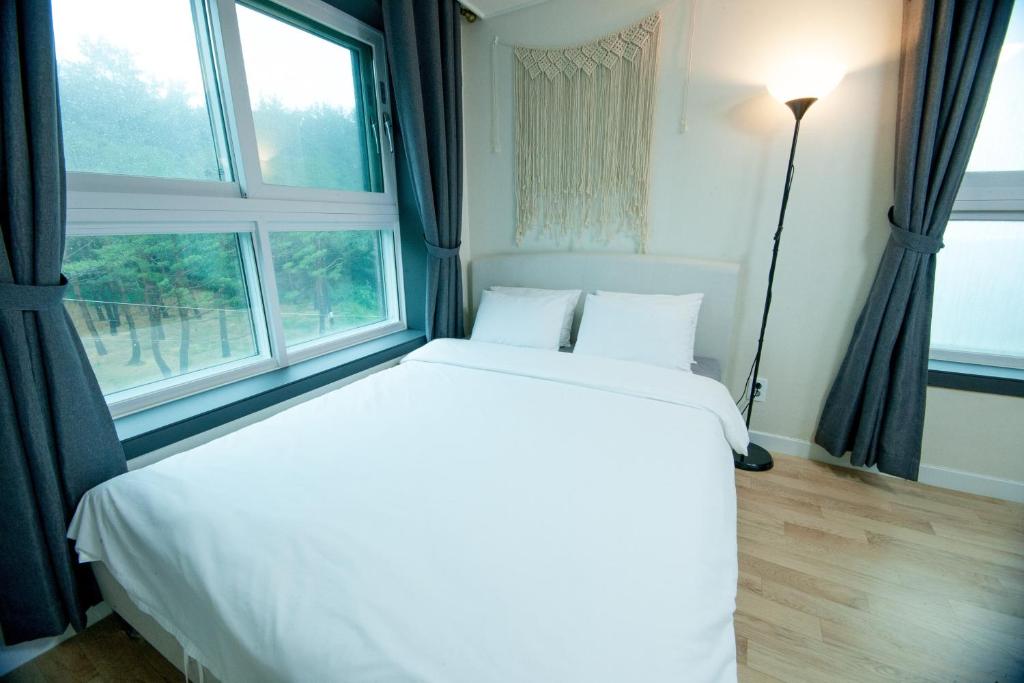 a white bed in a room with a window at Yangyang Ocean Hill in Yangyang