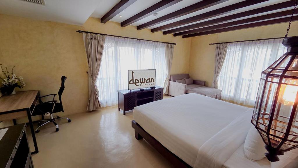 A bright bedroom with a large bed, sofa, desk, and two curtained windows.