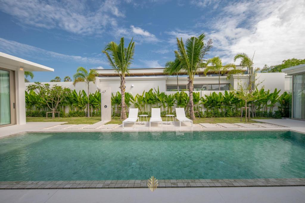 a swimming pool in front of a house with palm trees at Asherah Villa By Asherah Team in Ban Phru Champa