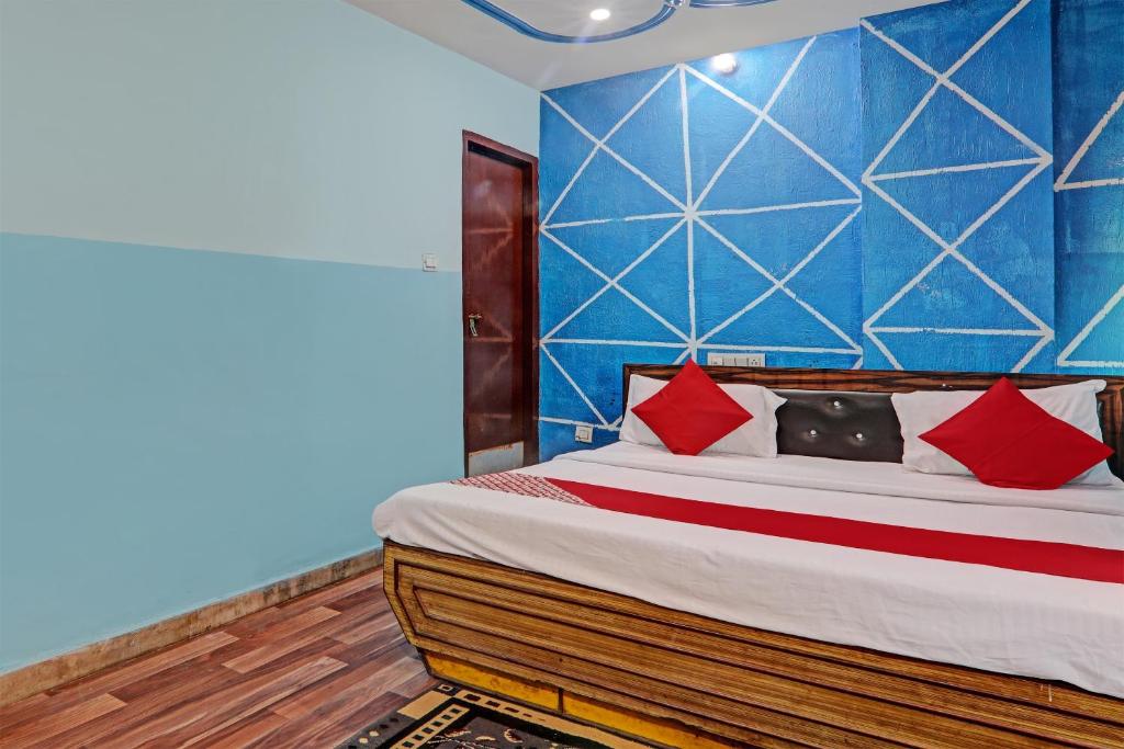 a bedroom with a bed with red pillows and a blue wall at Hotel O White Swan in Vibhuti Khand