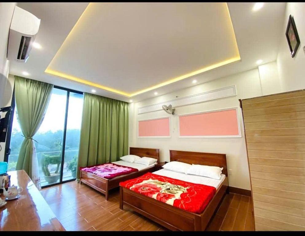 a bedroom with two beds and a large window at Thiên Kim Hometel in Liên Trì (4)