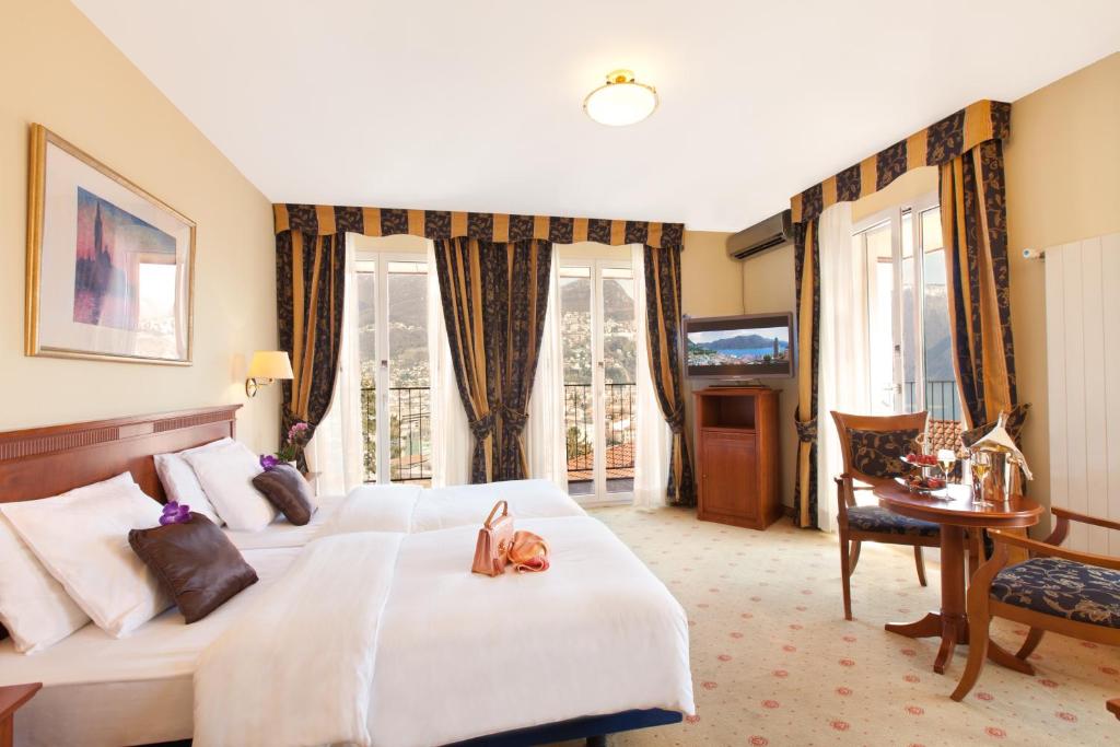 a hotel room with a bed and a desk and windows at Hotel Federale in Lugano