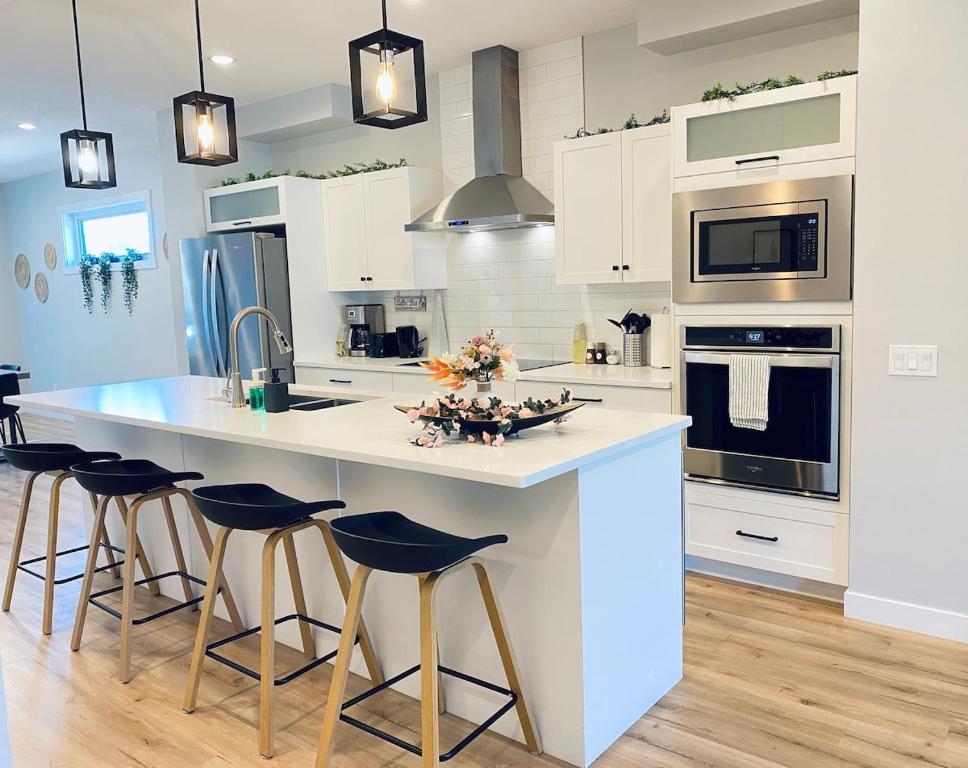 a kitchen with a large white island with bar stools at The Downtown Oasis - A Spacious Family Friendly 3 Bedroom House Close to Everything in Edmonton