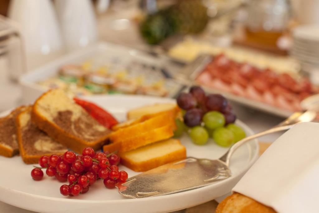 a plate of food with grapes and fruit on it at Hotel Federale in Lugano