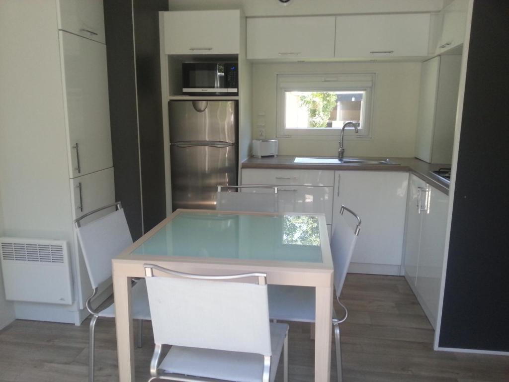 a kitchen with a glass table and white chairs at Rives Nature in La Gacilly