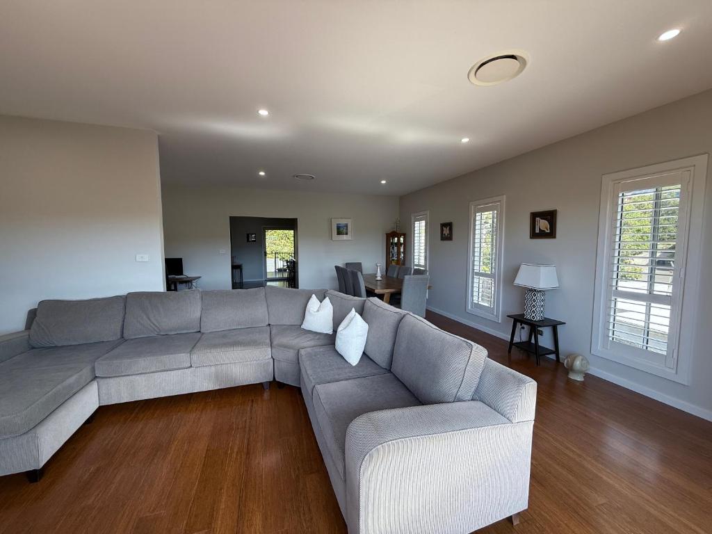 a living room with a gray couch and wooden floors at 500m to Werri Beach - The Palms in Gerringong