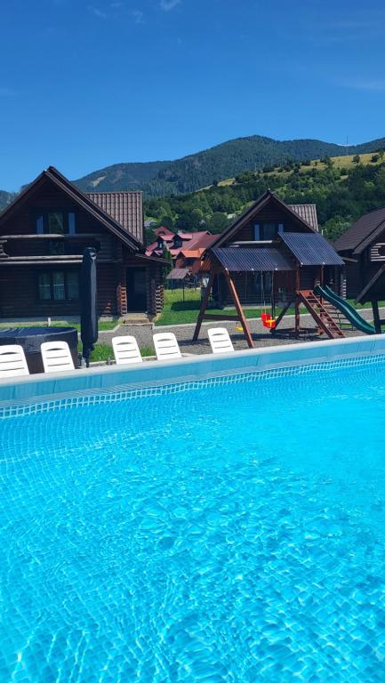 a large swimming pool with chairs and a house at Котеджі Карпати Fest in Mizhhirʼʼya