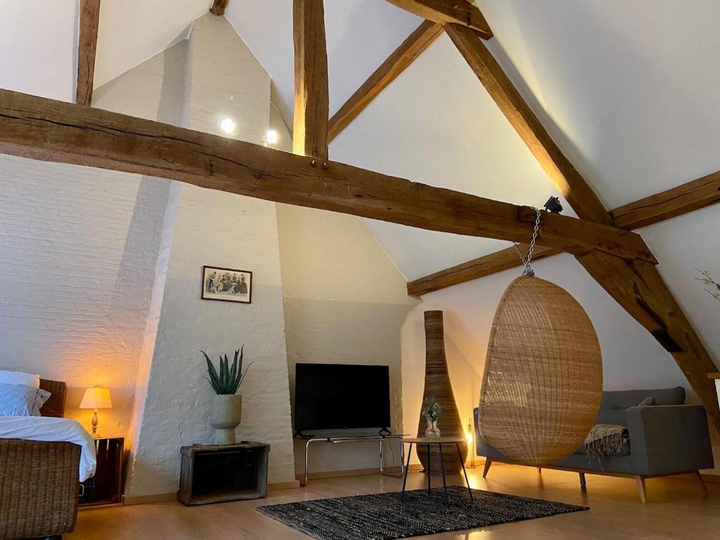 ein Zimmer mit einem Bett und einem Fernseher auf einem Dachboden in der Unterkunft Romantic Loft, historic farmhouse, Sauna, Nature walks in Schilde